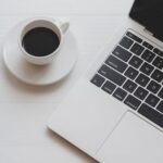 short-story Top view of minimal workplace with laptop computer and a cup of coffee on white wooden table